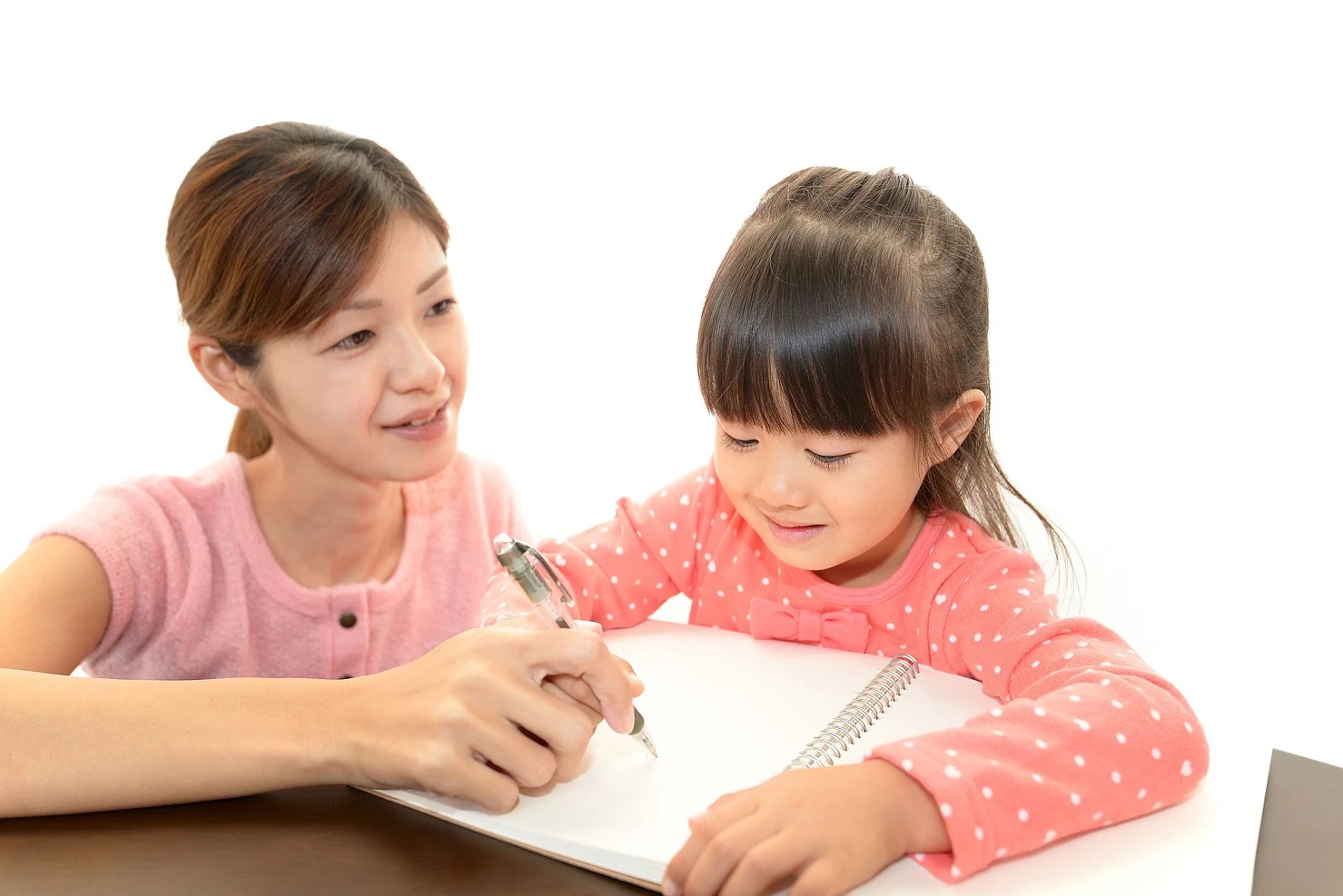 An adult guiding a child through written work, from the existing website