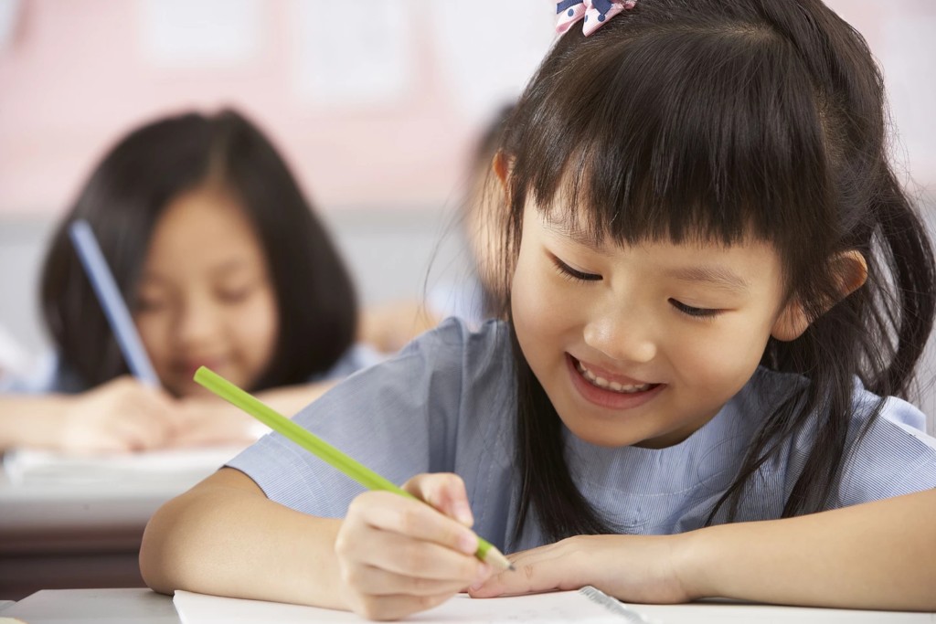 A child concentrating on her writing, from the existing LearningMAX website